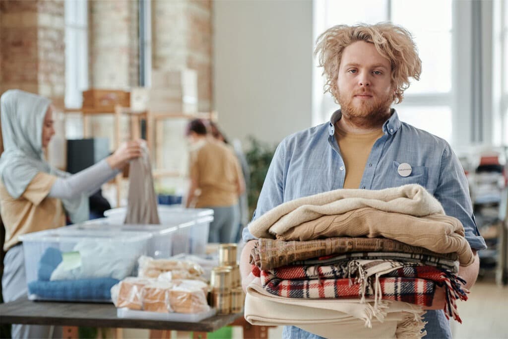 Man holding donated overstock blankets